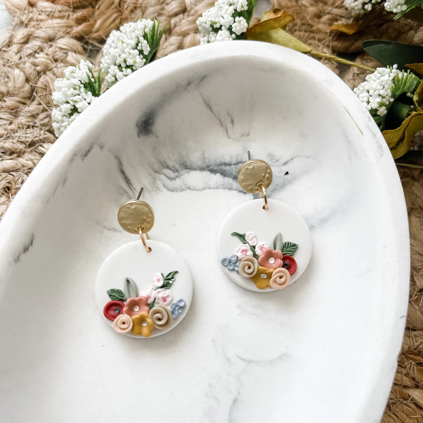 white clay dangling earrings with gold hardware and colorful floral design