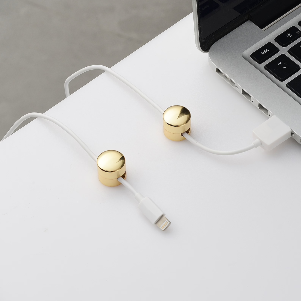 two gold button cable organizers on a table holding white cords