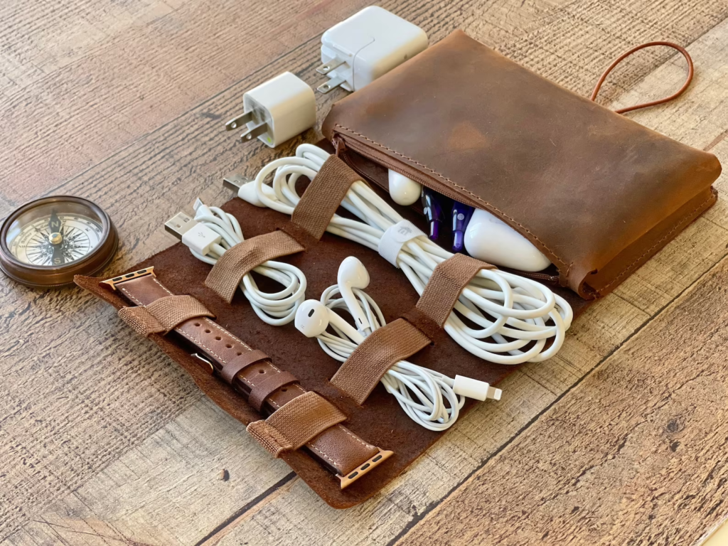 brown leather bag with cords, plugs, and headphones